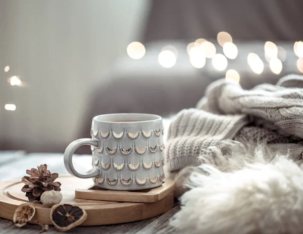 Xícara de café sobre luzes de Natal bokeh em casa na mesa de madeira com suéter em um fundo e decorações. Decoração de férias, Natal mágico — Fotografia de Stock