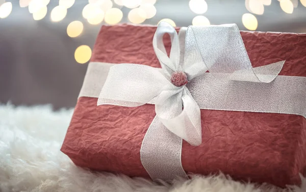 Gran regalo rojo sobre luces de Navidad bokeh en casa en la mesa de madera. Decoración navideña, Navidad mágica — Foto de Stock