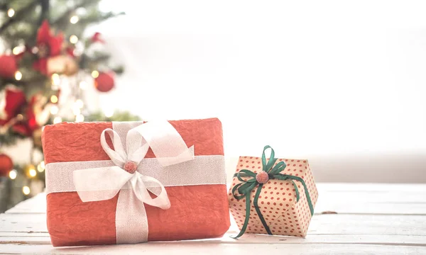 Κόκκινο χριστουγεννιάτικο δώρο πάνω από το φως φόντο στο ξύλινο τραπέζι κοντά στο παράθυρο. Χριστουγεννιάτικα στολίδια — Φωτογραφία Αρχείου