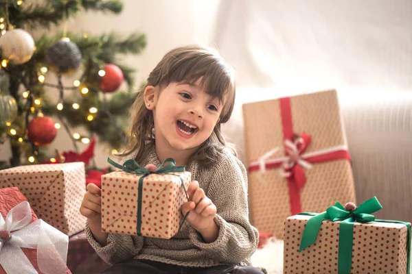 Sevimli küçük kız bir hediye kutusu tutarak ve onun yatağında onun odasına evde otururken gülümseyen