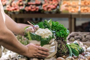 Hafta sonu çiftçi pazarında pamuk torba içinde taze olgun organik brokoli, yeşillik ve sebze ile salata tutan kadın elleri