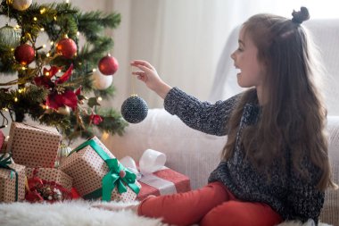 Noel ağacı ve SMI üzerine süslemeleri koyarak güzel küçük kız