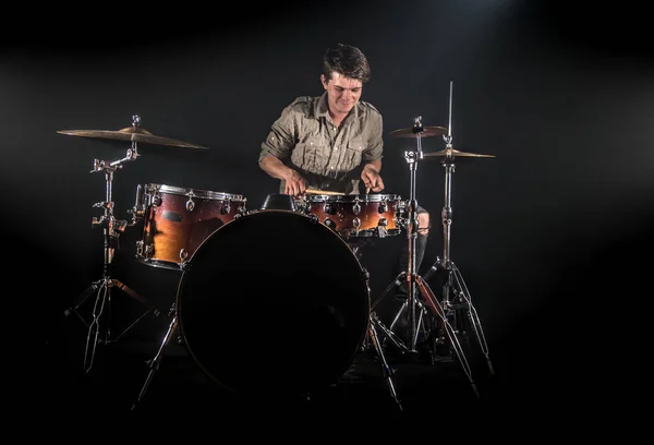 Professional drummer playing on drum set on stage on the black b
