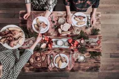 Arkadaşların elleri birlikte yiyip içiyor. Ahşap rustik masada birlikte parti yapan, toplayan, kutlayan insanların üst görünümü