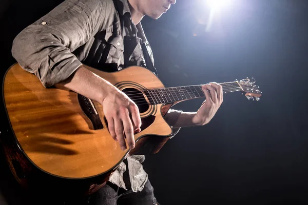 Guitarrista, música. Um jovem toca guitarra acústica num blac — Fotografia de Stock