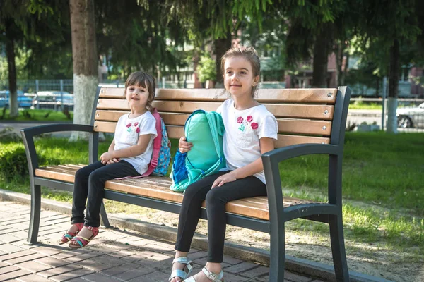 Okula dönüyoruz. Bankta oturan mutlu sevimli çalışkan çocuklar — Stok fotoğraf