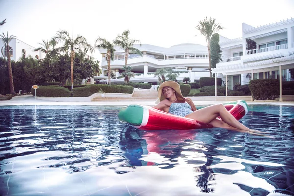 Summer holiday by the pool . Woman relaxes on an inflatable circ