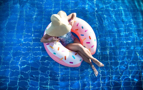 Una donna con un cappello si rilassa su un cerchio gonfiabile in piscina . — Foto Stock