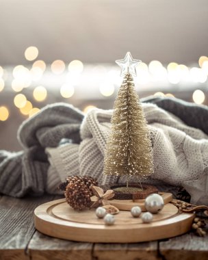 Noel ışıkları bokeh üzerinde küçük Noel ağacı bir arka plan ve süslemeleri üzerinde kazak ile ahşap masada evde. Tatil dekorasyonu