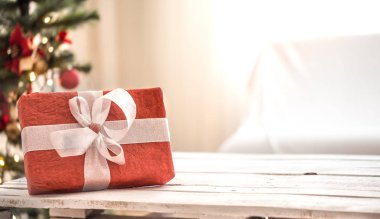 Rahat halı üzerinde ışık arka plan üzerinde Noel ışıkları ve Noel ağacı üzerinde Kırmızı Noel hediyesi. Noel süsleri