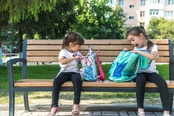 De volta à escola. Feliz bonito industrious crianças sentadas no banco e falando. Conceito de educação bem sucedida . — Fotografia de Stock