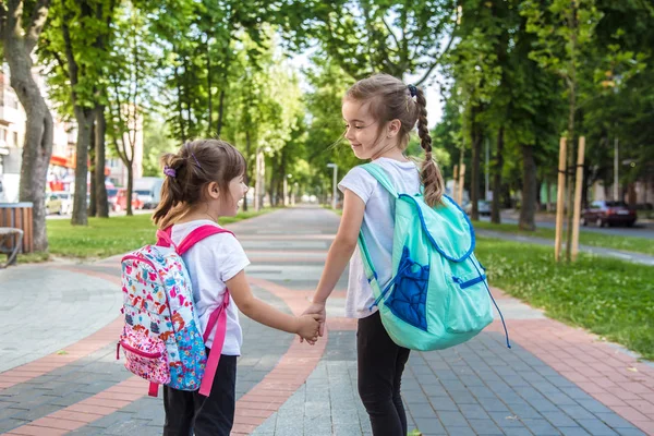 De volta ao conceito de educação escolar com garotas, alunos do ensino fundamental, carregando mochilas indo para a aula — Fotografia de Stock