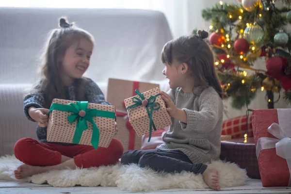 Jolies petites filles tiennent une boîte-cadeau et sourient à la maison sur fond clair — Photo