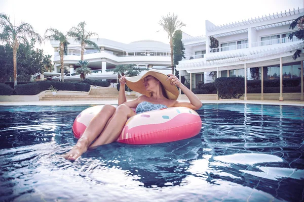 Vacaciones de verano junto a la piscina. Mujer en una rosquilla inflable —  Fotos de Stock