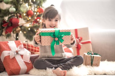 Güzel küçük kız bir hediye kutusu tutuyor ve zaman Sitti gülümseyen