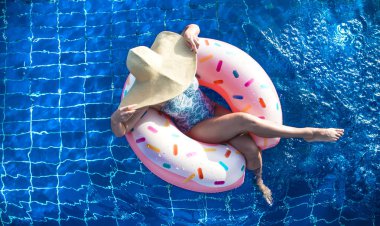 Şapkalı bir kadın havuzda şişme bir daire üzerinde rahatlatır.