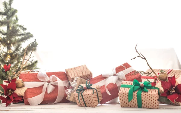 Montón de regalos de Navidad sobre luces de Navidad y árbol de Navidad sobre fondo claro sobre mesa de madera. Decoraciones de Navidad —  Fotos de Stock