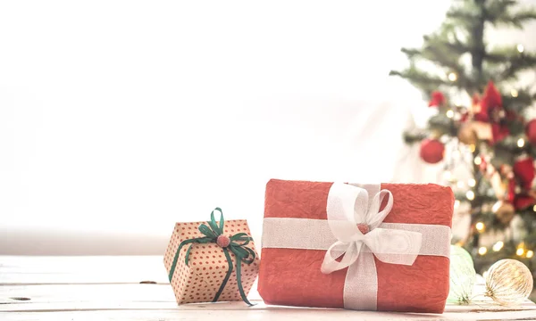 Cadeau de Noël rouge sur les lumières de Noël et l'arbre de Noël sur fond clair sur un tapis confortable. Décorations de Noël — Photo