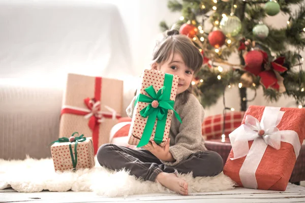 Sevimli küçük kız bir hediye kutusu tutarak ve onun yatağında onun odasına evde otururken gülümseyen
