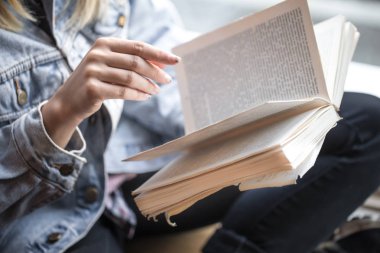 Bir kafede oturan ve kitap okuyan genç kız