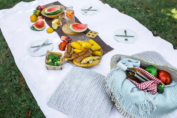 Una manta blanca sobre la hierba verde. El concepto de un picnic . — Foto de Stock