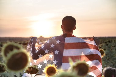 Bir adam gün batımında Bir Amerikan bayrağı tutar.