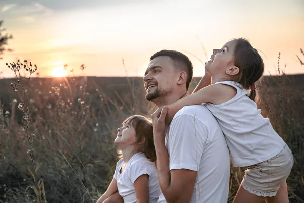 Dad and his daughters in the field at sunset . — Stock Photo, Image