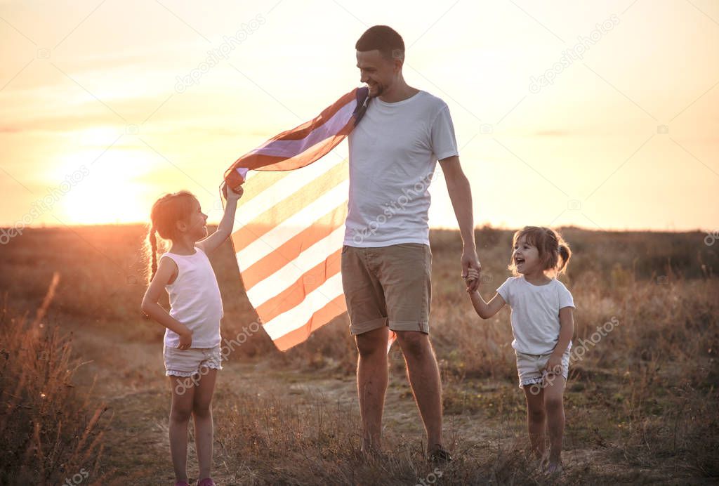 A happy family with an American flag at sunset.