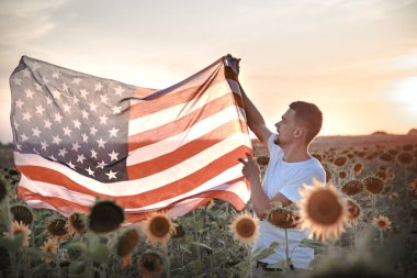 Bir adam gün batımında Bir Amerikan bayrağı tutar.