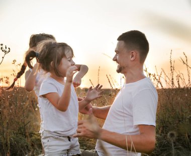 Baba ve kızları gün batımında tarlada .