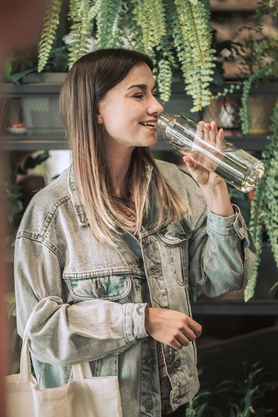 Niña bebiendo agua de una botella de vidrio con una eco-bolsa en — Foto de Stock