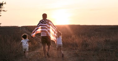 Gün batımında Amerikan bayrağı olan mutlu bir aile.