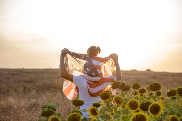 Szczęśliwa rodzina z amerykańską flagą o zachodzie słońca. — Zdjęcie stockowe