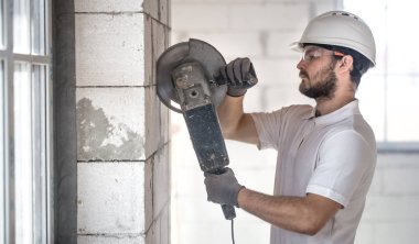 Endüstriyel İnşaatçı profesyonel açılı öğütücüyle çalışıyor.