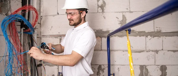 Elettricista che lavora vicino al Consiglio con fili. Installazione e — Foto Stock