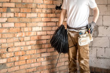 Aletleri olan bir elektrikçi, inşaat alanında çalışıyor. Tamir et.