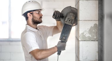 Endüstriyel İnşaatçı profesyonel açılı öğütücüyle çalışıyor.
