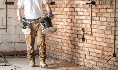 Aletleri olan bir elektrikçi, inşaat alanında çalışıyor. Tamir et.