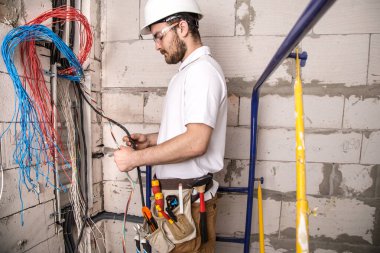 Kurulun yanında kablolarla çalışan bir elektrikçi. Kurulum ve 