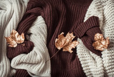 Sonbahar arkaplanı rahat süveterler ve altın yapraklarla .