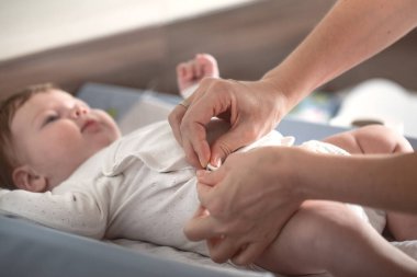 Annem yeni doğmuş bir bebeği soyunma masasına yatırır. .