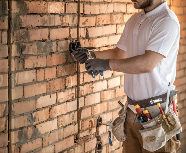 Installatore elettrico con uno strumento in mano, che lavora con la cabina — Foto Stock