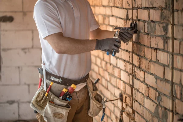 Electrician installer with a tool in his hands, working with cab — Stock Photo, Image