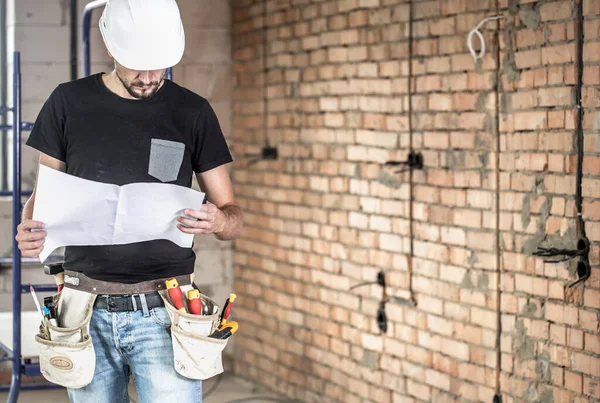 Builder handyman with construction tools, looking at the drawing — Stock Photo, Image