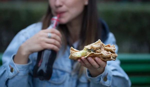 길거리에서 패스트푸드를 먹는 젊은 여자. — 스톡 사진