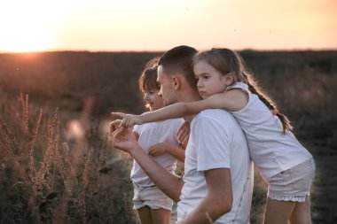 Baba ve kızları gün batımında tarlada .