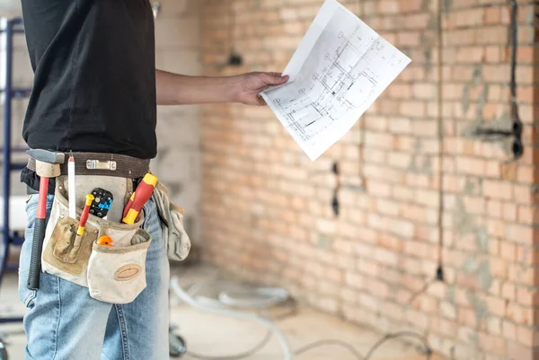Builder handyman with construction tools, looking at the drawing — Stock Photo, Image