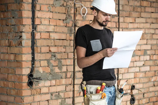 Builder handyman with construction tools, looking at the drawing — Stock Photo, Image