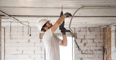 Tamirci, tesis için matkap kullanıyor. Profesyonel işçi. 