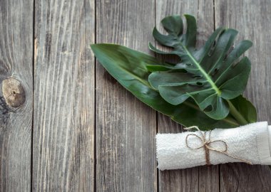 Havlular ve ahşap bir sırtta tropikal yapraklı spa kompozisyonu.